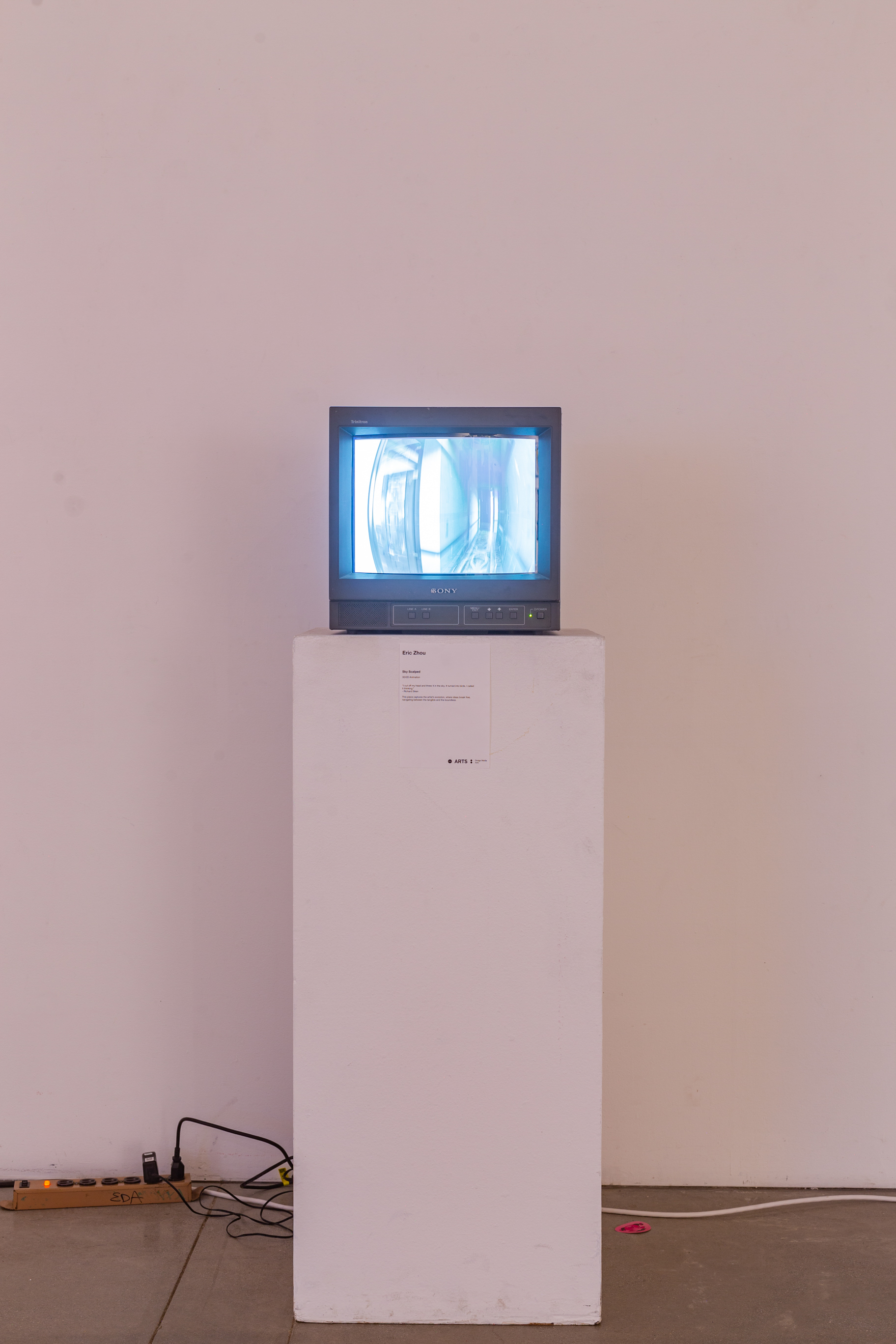 A CRT TV sits on top of a white podium with a white wall in the background.